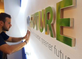 Man installing large green 3D letters for an exhibition space.