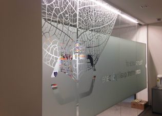Modern exhibition space with artistic glass wall design and branding elements.