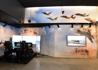 Modern exhibition space featuring flight simulators and aircraft murals.
